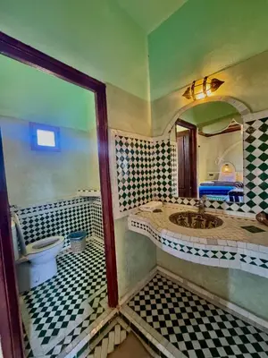 a bathroom with a toilet and a sink and a mirror at AUBERGE KSAR MERZOUGA in Merzouga