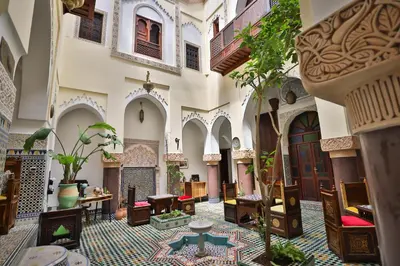 a courtyard of a building with tables and chairs at Riad Le Moucharabieh in Fès