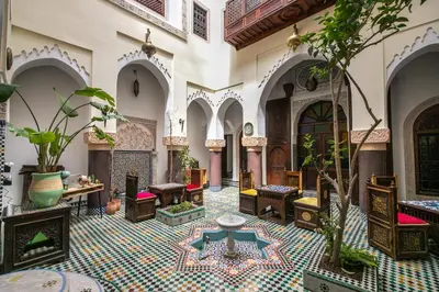 a courtyard with chairs and tables in a building at Riad Le Moucharabieh in Fès