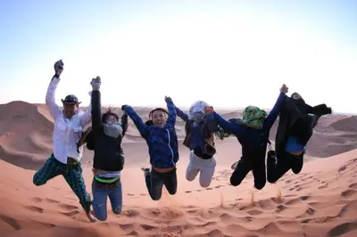 a group of people jumping in the desert at Desert Camel Trekking Camp in Hassilabied