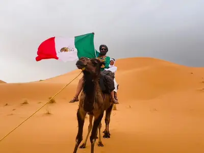a man and a child riding a camel in the desert at Desert Camel Trekking Camp in Hassilabied