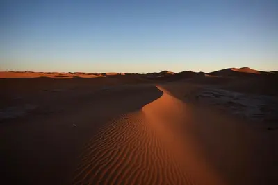a desert with the sun shining on the sand at Bivouac ZAGORA in Zagora