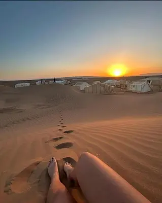 a woman laying on the sand in the desert at Bivouac ZAGORA in Zagora