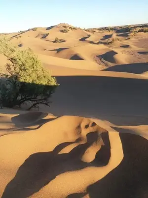 a person laying in the sand in a desert at Nomadic Stay in Mhamid