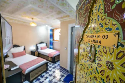 a hotel room with two beds and a sign on a door at Hotel & Ryad DALILA in Fès