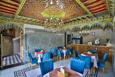 a restaurant with blue chairs and tables and a chandelier at Hotel & Ryad DALILA in Fès