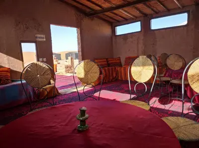 a room with chairs and a table with a red rug at Bivouac Le charme d'Aladdin in El Gouera