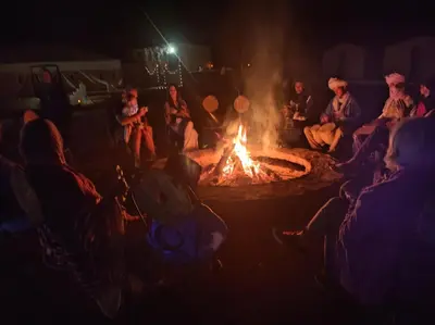a group of people sitting around a fire at Bivouac Le charme d'Aladdin in El Gouera
