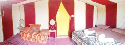 a bedroom with a bed and a chair at Bivouac Le charme d'Aladdin in El Gouera