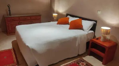 a bedroom with a large white bed with orange pillows at Côté Sud in Ouarzazate