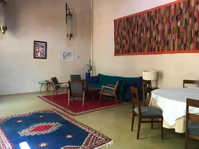 a dining room with a table and chairs and a rug at Côté Sud in Ouarzazate