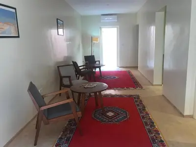 a living room with chairs and a table and a red rug at Côté Sud in Ouarzazate