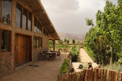 a building with a table and chairs in a garden at AZIGHAME Complexe Touristique in Tinerhir