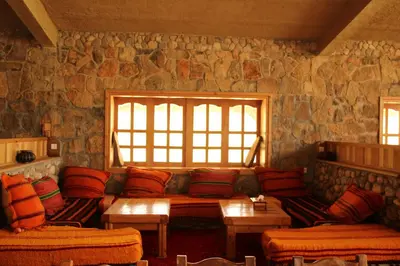 a living room with a couch and a stone wall at AZIGHAME Complexe Touristique in Tinerhir
