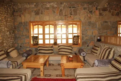 a living room with couches and a table and a window at AZIGHAME Complexe Touristique in Tinerhir