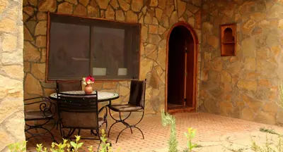 a table and chair in front of a stone building at AZIGHAME Complexe Touristique in Tinerhir