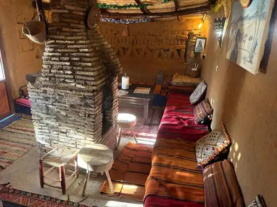 a living room with a couch and a stone fireplace at kasbah planet sahara in Merzouga