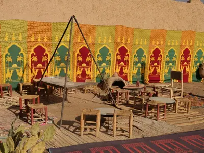 a group of tables and chairs in front of a wall at kasbah planet sahara in Merzouga