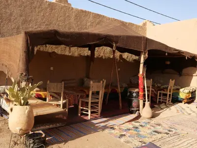 a tent with a table and chairs under it at kasbah planet sahara in Merzouga