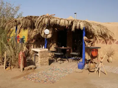 a small hut with a thatched roof in the desert at kasbah planet sahara in Merzouga