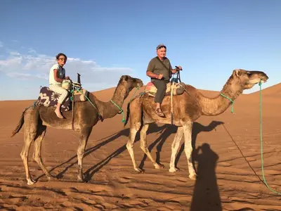 two people riding on camels in the desert at Erg Chegaga Camp & Activites in Mhamid