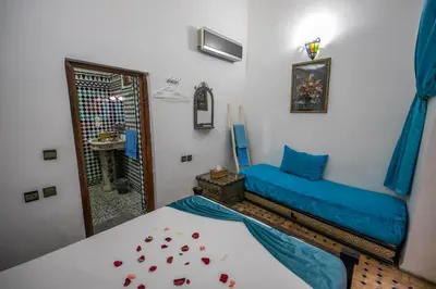 a bedroom with a blue bed and a mirror at Riad Dar Rabha in Fès