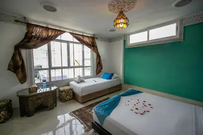 a bedroom with two beds and a large window at Riad Dar Rabha in Fès