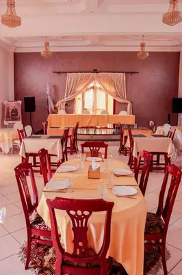 a dining room with tables and chairs and a stage at Salma Palms Hôtel in Madkhal Meski