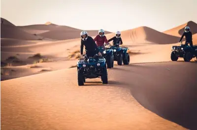 a group of people riding atvs in the desert at Luxury traditional Tent Camp in Merzouga