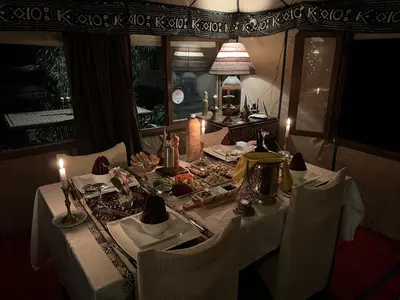 a dining room table with a white table cloth and candles at Luxury traditional Tent Camp in Merzouga