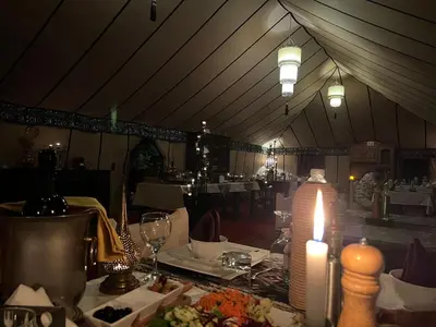 a dining room with a table with a lit candle at Luxury traditional Tent Camp in Merzouga