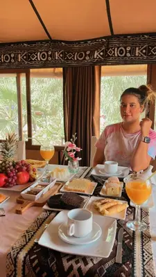 a woman sitting at a table with food at Luxury traditional Tent Camp in Merzouga