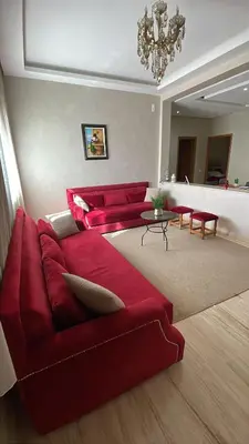 a living room with a red couch and a chandelier at Suites Appartement Midelt in Midelt