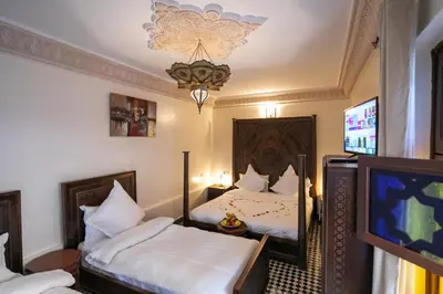 a bedroom with two beds and a tv and a chandelier at Riad Anis Fes in Fès