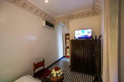 a room with a bed and a tv on a wall at Riad Anis Fes in Fès