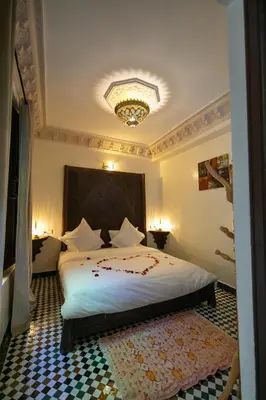 a bedroom with a large bed with a chandelier at Riad Anis Fes in Fès