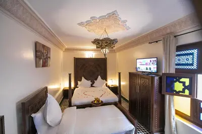 a bedroom with two beds and a flat screen tv at Riad Anis Fes in Fès