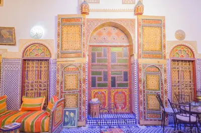 a room with colorfulfully decorated doors and a table and chairs at Riad Hayat Fes in Fès