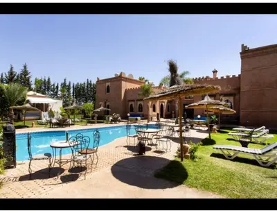 a pool with tables and chairs next to a house at Palace with 2 villas and 2 swimming pools in Sidi Abdellah Ghiat in Had Abdallah Rhiat