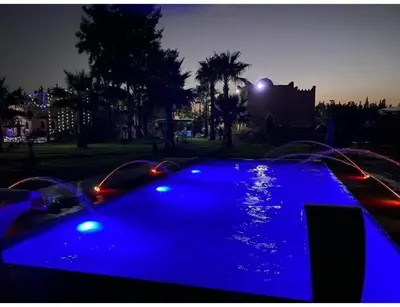 a swimming pool with blue lights in a park at night at Palace with 2 villas and 2 swimming pools in Sidi Abdellah Ghiat in Had Abdallah Rhiat