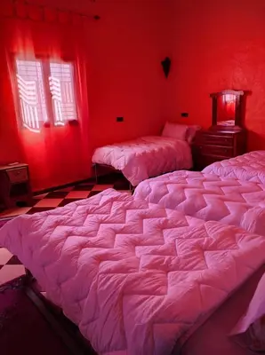 two beds in a room with red walls at Riad gnaoua khamlia in Merzouga