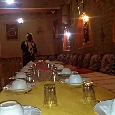 a table with white plates and a person in a room at Riad gnaoua khamlia in Merzouga