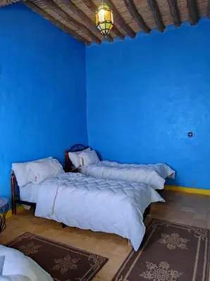 two beds in a room with a blue wall at Riad gnaoua khamlia in Merzouga