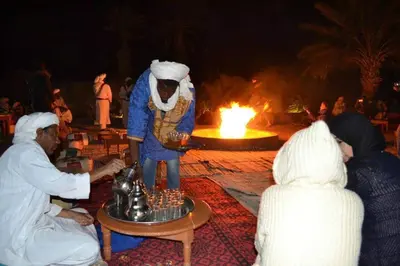 a group of people standing around a statue in front of a fire at Riad gnaoua khamlia in Merzouga
