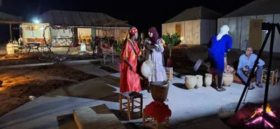 a group of people in costumes standing next to a fire at Abdo Luxury Camp with Heating in Merzouga