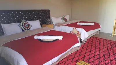 two beds in a room with red and white sheets at Abdo Luxury Camp with Heating in Merzouga