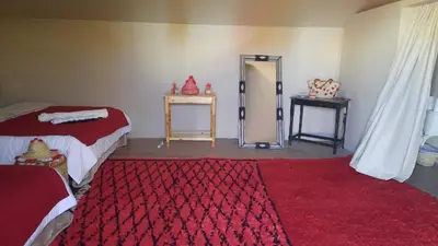a room with a bed and a mirror and a red rug at Abdo Luxury Camp with Heating in Merzouga
