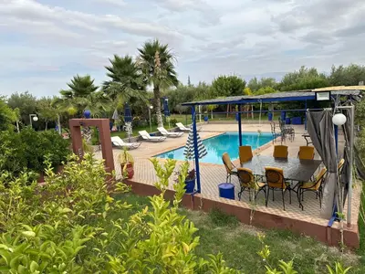 a swimming pool with a table and chairs next to it at Villa yanii siin in Marrakech