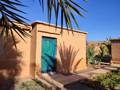 a building with a blue door and a palm tree at Maison d'hôtes Tigminou - Adults Only in Aït Ben Haddou