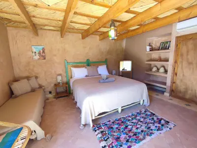 a bedroom with a large bed and a couch at Maison d'hôtes Tigminou - Adults Only in Aït Ben Haddou